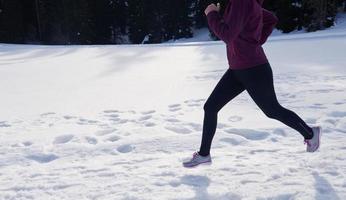 jeune femme faisant du jogging en plein air sur la neige en forêt photo