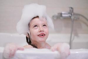 petite fille dans le bain jouant avec de la mousse de savon photo