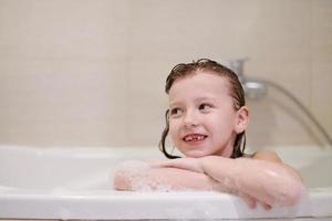 petite fille dans le bain jouant avec de la mousse de savon photo