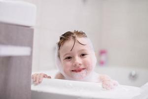 petite fille dans le bain jouant avec de la mousse de savon photo