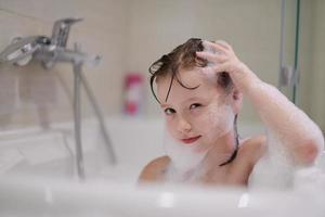 petite fille dans le bain jouant avec de la mousse de savon photo