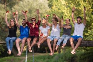 amis appréciant la pastèque assis sur le pont en bois photo