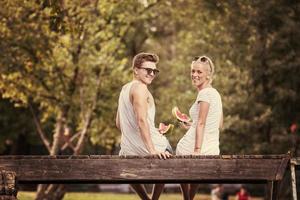 couple profitant de la pastèque assis sur le pont en bois photo