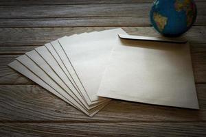 Enveloppe de lettre brune avec globe sur table en bois photo