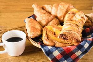 assortiment de pâtisseries avec une tasse de café sur fond de table en bois. photo