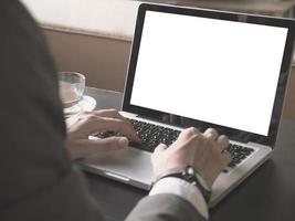 gros plan d'un homme d'affaires utilisant un ordinateur portable avec écran blanc sur le bureau. photo