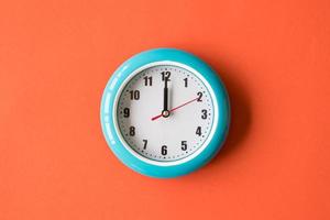 horloge murale bleue sur fond orange, douze heures photo