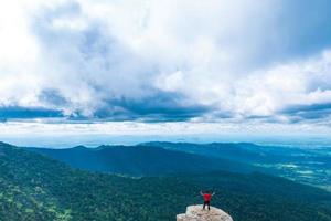 jeune homme profitant d'une vue sur la vallée du haut d'une montagne. photo