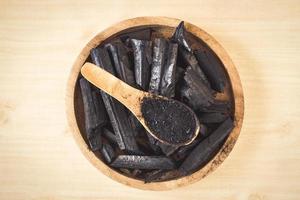 charbon de bois et poudre de charbon de bois sur fond de table en bois. photo