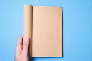 vue de dessus des mains tenant un livre vierge prêt avec un espace de copie prêt pour le texte sur fond bleu. photo