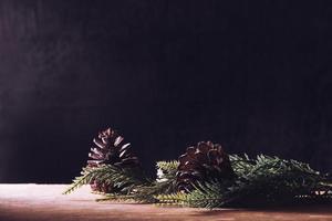 pommes de pin avec des branches sur la table en bois, fond noir, espace libre pour le texte photo