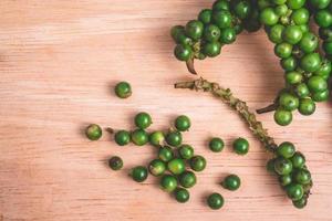 grains de poivre vert sur fond en bois. photo