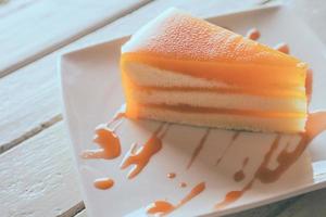 gâteau orange dans un plat blanc sur la table en bois. photo