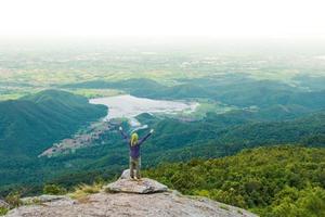 jeune homme profitant d'une vue sur la vallée du haut d'une montagne. photo