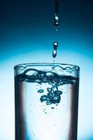 verser de l'eau dans le verre sur fond bleu. photo