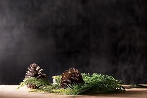 pommes de pin avec des branches sur la table en bois, fond noir, espace libre pour le texte photo