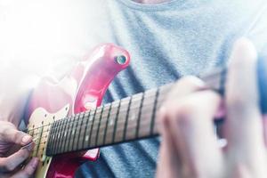 gros plan sur des mains masculines jouant de la guitare électrique, éclat de la lumière du soleil, mise au point sélective photo