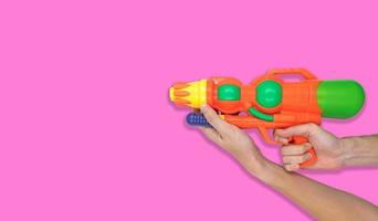 main tenant un jouet d'eau de pistolet sur fond rose. espace libre pour le texte photo