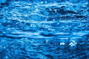 vague bleue et bulles sur fond de surface de l'eau. photo