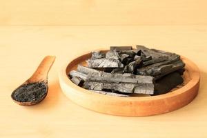 charbon de bois et poudre de charbon de bois sur fond de table en bois. photo