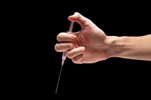 main masculine tenant une seringue d'outil médical sur fond noir.