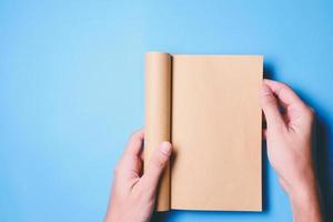 vue de dessus des mains tenant un livre vierge prêt avec un espace de copie prêt pour le texte sur fond bleu. photo