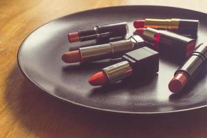 rouges à lèvres colorés sur la plaque noire au-dessus de la table en bois. concept de maquillage et de beauté photo