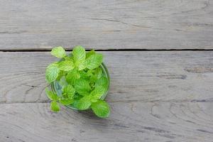 menthe dans le bol en verre transparent sur fond de bois photo