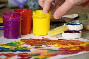 main d'une fille mélangeant les couleurs avec les doigts pour la peinture. peinture abstraite à la gouache. peinture au doigt photo