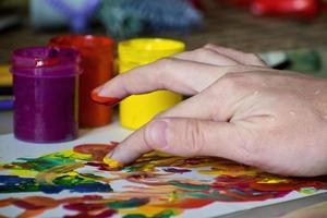 main d'une fille mélangeant les couleurs avec les doigts pour la peinture. peinture abstraite à la gouache. peinture au doigt photo