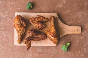 vue de dessus des cuisses et des ailes de poulet frites sur un plateau en bois.