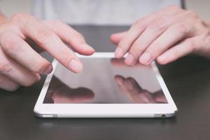 gros plan des mains masculines à l'aide d'une tablette sur la table. photo