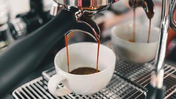 gros plan d'espresso coulant de la machine à café coulant dans la tasse à café faire du café pour les clients du café. photo