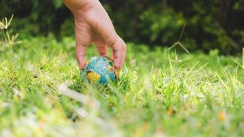 la planète terre dans les mains du garçon sauve et protège le monde sur fond de nature verte floue. concept environnemental le jour de la terre. photo