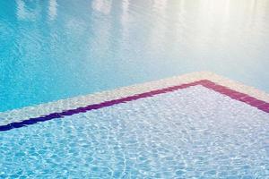 fond d'eau dans une piscine bleue, surface de l'eau avec un reflet du soleil photo