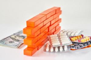 les pilules médicales et les billets d'un dollar séparent l'argent avec un mur de briques de jouets