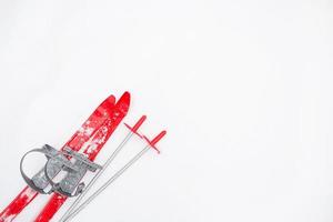 skis rouges pour enfants avec bâtons -disposition dans la neige. sports d'hiver pour enfants, activités de plein air, plaisir en famille. fond givré naturel blanc. espace de copie. photo