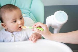 maman nourrit le bébé avec une cuillère de purée de légumes à la table d'alimentation des enfants. l'appétit du bébé, une alimentation saine, l'introduction d'aliments complémentaires. copyspace, maquette photo