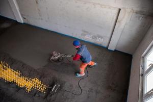 travailleur exécutant et polissant un sol en chape de sable et de ciment photo