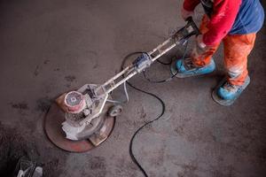 travailleur exécutant et polissant un sol en chape de sable et de ciment photo