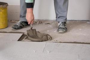 travailleur installant les carreaux en céramique effet bois sur le sol photo