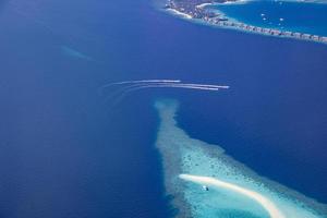 photo aérienne du lagon de l'océan tropical bleu turquoise, plage de sable blanc, eau peu profonde du récif corallien de banc de sable avec un bateau. perfection de la nature dans la mer des maldives. expérience de vie de luxe, paysage paisible