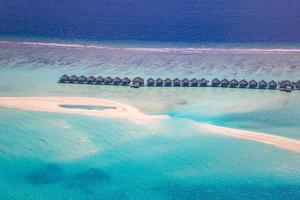 paysages paradisiaques des maldives. paysage aérien tropical, paysage marin avec longue jetée, villas sur l'eau avec une magnifique plage de mer et de lagon, nature tropicale. bannière de destination touristique exotique, vacances d'été photo