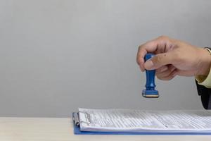 homme tamponnant l'approbation des documents bancaires de financement du travail ou de marketing d'investissement sur le bureau. photo