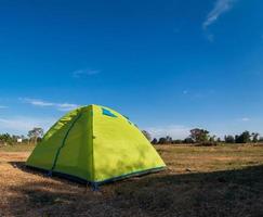 voyageur vert tente camping voyage en plein air. vue depuis la tente à l'intérieur sur le soleil bleu du ciel dans le paysage d'été. le soir de la journée propice au sommeil et au repos du corps photo