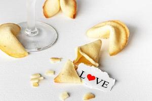 biscuits en forme de tortellini avec le mot amour écrit sur un papier et un verre de champagne.image horizontale. photo