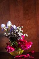 Diverses fleurs dans un vase sur fond marron foncé photo