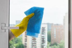 laver le verre de la fenêtre de la maison par un chiffon bleu photo