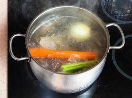 bouillon de viande bouillante dans une marmite sur une cuisinière en céramique photo