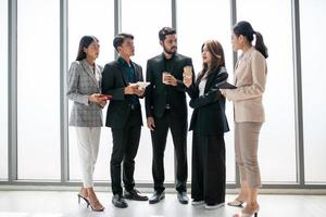 les collègues masculins et féminins de l'équipe commerciale qui parlent au travail partagent des idées avec un rapport de données entre les mains, des collègues heureux travaillent ensemble au bureau. photo